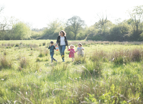 Woman and children walking through a field in sunshine