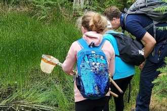Photo showing young people visiting Brownsea Island with a girl with a net in her hand