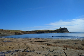 A landscape photo of Kimmeridge bay with blue sky and sunshine