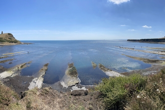 A view of Kimmeridge Bay looking out to sea taken at low tide with rocky ledges exposed