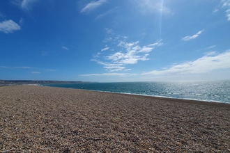 A photo of Chesil Beach looking towards Portland under blue skies