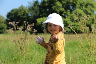 Girl in meadow with bug pot