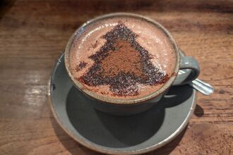 A mug of hot chocolate with a christmas design on top