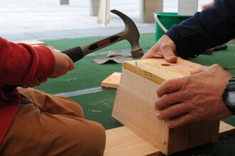 Picture of a child using a hammer to build a bird nest box.