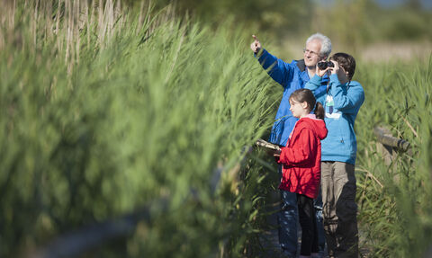 Photo of man and 2 children birdwatching