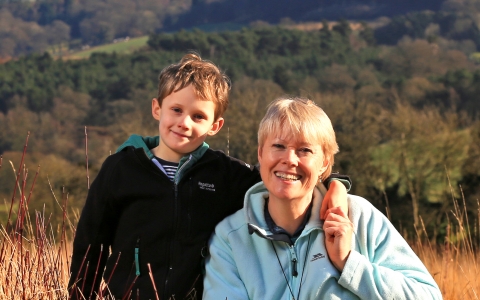 Kati and her son sat in a field with woods in background