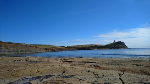 A landscape photo of Kimmeridge bay with blue sky and sunshine