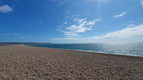 A photo of Chesil Beach looking towards Portland under blue skies