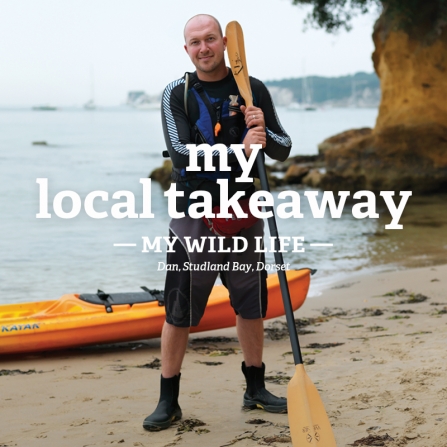 Dan stands on a beach with his kayak