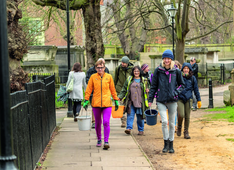Group of people walking in London with gardening equipment in late winter