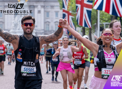Photo of two people holding hands in the air as they run the London Marathon